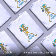 Футболка життя мандрівка, біла, зображена з правого боку, на фоні градієнтного сірого, принт з малюнком скелета, який йде з мішком, текст "ВСЕ ЖИТТЯ МАНДРІВКА" внизу.