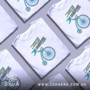 Футболка життя це подорож, біла футболка з принтом велосипеда, зображена з фронтального ракурсу на манекені, фон нейтральний, принт виконаний у блакитному та жовтому кольорах.