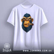 Футболка зла мавпа, біла, підвішена на вішалці, фон світло-сірий, принт з обличчям мавпи з сигарою, деталі принта чіткі та яскраві.