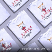 Футболка злюка вередуля, білого кольору, зображена на манекені, фон світло-сірий, принт з малюнком дівчинки з рудими волоссям у двох кісках, що тримає цукерку, текст червоним і чорним кольором.