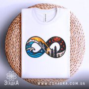 Футболка знак нескінченності, біла, складена на плетеній кошику, фон світло-сірий, принт з елементами гір, хвиль та лісу в яскравих кольорах, видно деталі принта.