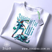 Футболка знищити ШІ, білого кольору, складена на поверхні, фон світло-сірий, принт з дівчиною, що тримає фарбу, з тегом на комірці.