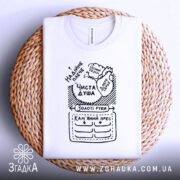 Футболка золоті руки, біла, складена на плетеній основі, фон світлий, принт чорного кольору з написами та малюнками, включаючи фрази 'Чиста душа' та 'Золоті руки'.