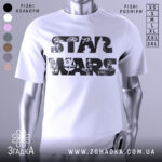 Футболка зоряні війни білого кольору, зображена на манекені з блискучого металу, фон світло-сірий, принт з написом 'STAR WARS' та ілюстраціями персонажів і кораблів з всесвіту Зоряних війн.