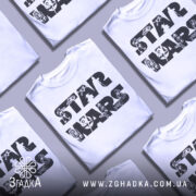 Футболка зоряні війни білого кольору, зображена на манекені з блискучого металу, фон світло-сірий, принт з написом 'STAR WARS' та ілюстраціями персонажів і кораблів з всесвіту Зоряних війн.