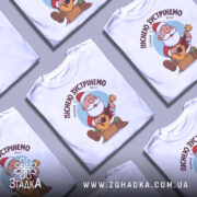 Футболка зустрінемо Новий Рік, біла, зображена на манекені, фон світло-сірий, принт з дідом Морозом, який грає на гітарі, текст зверху: 'Піснею зустрінемо Новий Рік!'