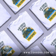 Футболка звичайний тракторист. Біла футболка з коротким рукавом, зображена з фронтального ракурсу на манекені. На фоні світло-сірий градієнт. Принт містить зображення трактора та текст: 'Я не блогер, не артист, я - звичайний тракторист' у зеленому та жовтому кольорах.