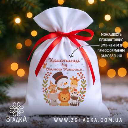 Іменна Торбинка до Миколая на фоні ялинки й вогників, білий габардин 20×30 см з червоною стрічкою та принтом зі сніговиком і звірятками.