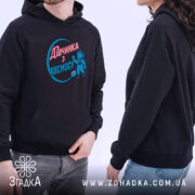 Худі дівчинка з космосу. Темно-синій худі на двох людях, один з яких показує принт. Вид з боку, фон світлий, акцент на капюшонах та кишені-«кенгуру».