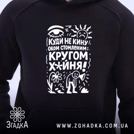 Худі кругом х*йня, чорного кольору, з капюшоном, з близького ракурсу, на фоні нейтрального кольору, з яскравим принтом на грудях, що містить текст і малюнки.