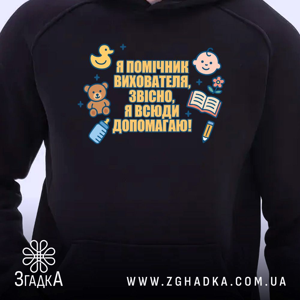 Худі помічник вихователя подарунок, чорного кольору, з капюшоном, на передньому плані видно принт з малюнками і текстом. Фон світлий, що підкреслює контрастність худі.