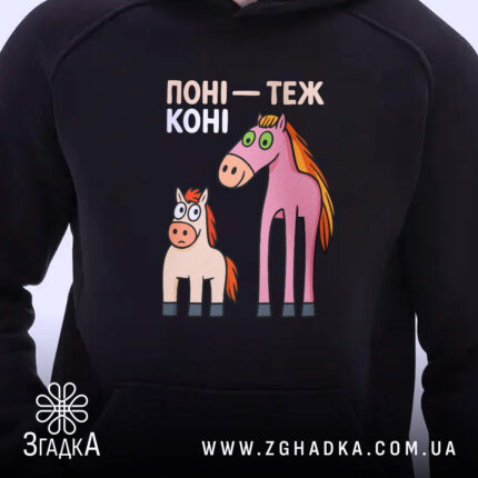 Худі поні теж коні. Темно-синій худі з капюшоном, ракурс близько, фон нейтральний. Принт з двома мультяшними поні: один рожевий, інший світло-коричневий, з великими очима. Кишеня-«кенгуру» не видно, манжети та пояс з еластичної тканини.