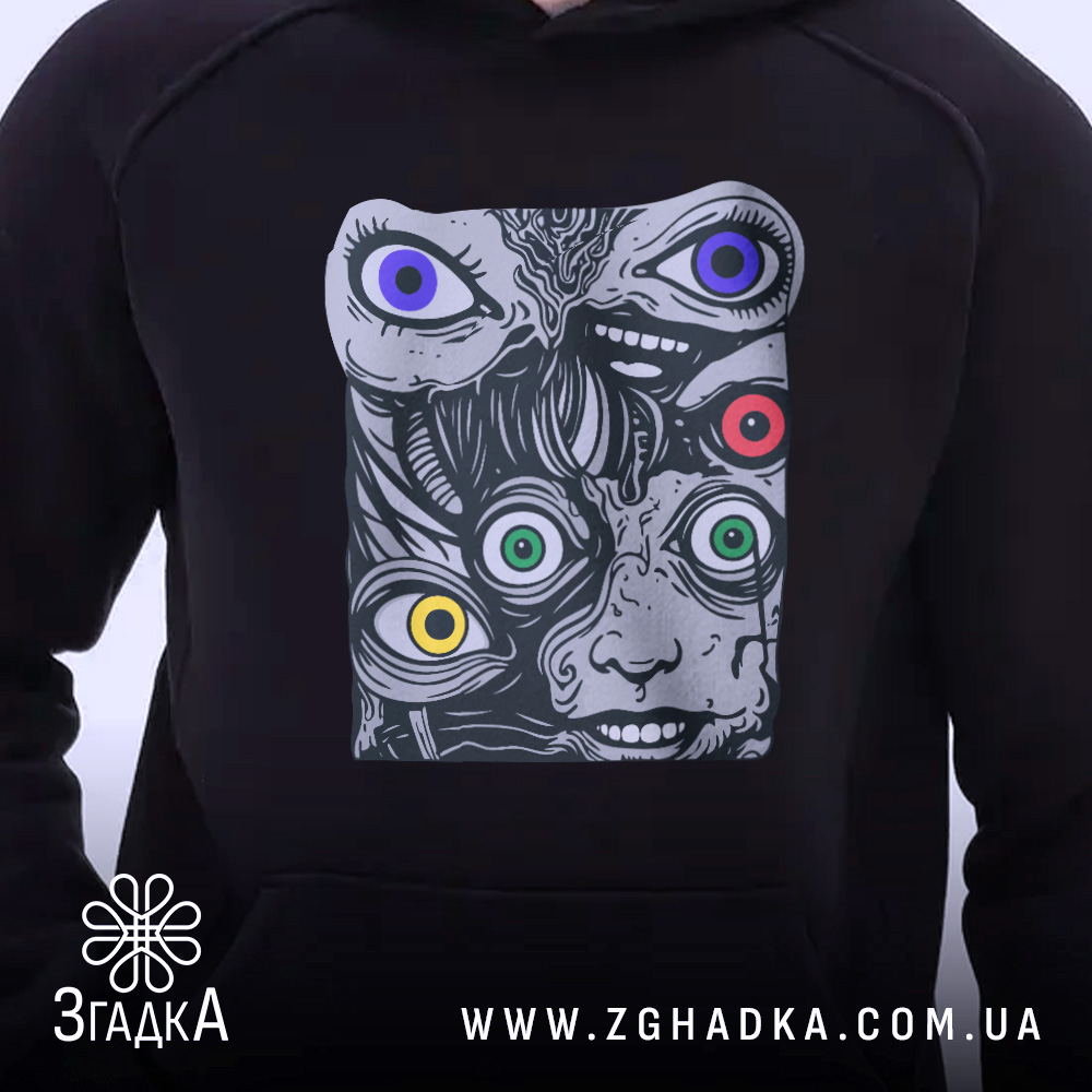 Худі психоделічні очі, чорного кольору, з капюшоном, зображене на людині, яка стоїть в анфас. Принт з абстрактними обличчями та кольоровими очима, добре видно деталі.