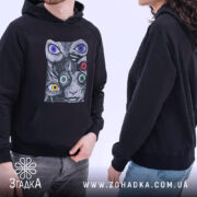 Худі психоделічні очі, чорного кольору, на двох людях, один з яких стоїть в анфас, а інший в профіль. Принт з абстрактними обличчями та кольоровими очима, капюшон та кишеня-«кенгуру» помітні.