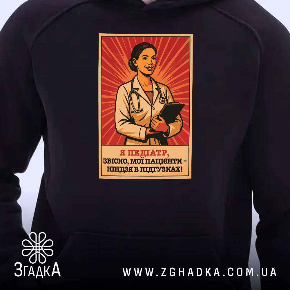 Худі стильний подарунок педіатру, темно-синього кольору, з близького ракурсу, на фоні видно принт з лікарем на червоному фоні, капюшон піднятий, деталі принта чітко видимі, є кишеня-«кенгуру», манжети та пояс з еластичної тканини.