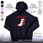 Худі з принтом динозавр, темно-синього кольору, зображене з ракурсу спереду, на фоні світлого простору. Принт з веселим динозавром, що тримає пляшку, виконаний у червоному та світло-кремовому кольорах. Кишеня-«кенгуру» розташована внизу, капюшон має класичну форму, манжети та пояс виконані в рибаній текстурі.