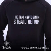 Худі зимові хуртовини, чорного кольору, з ракурсом спереду, на фоні світлого простору, з принтом на грудях білим шрифтом, капюшон присутній, без видимих манжетів чи кишень.
