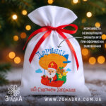 Мішечок для цукерок від Миколая на білому габардині 20×30 см, червона стрічка, персоналізація імені, святковий принт з дирижаблем.