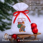 Мішечок до Дня Миколая на санчатах у снігу, білій габардиновий 20×30 см, червона зав’язка, поруч ялинкові кулі.