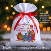 Мішечок до Дня Миколая на фоні ялинки й вогників, білий габардин 20×30 см з червоною стрічкою та принтом Святого Миколая.