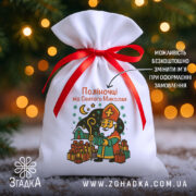 Мішечок дитячий до Миколая — білий габардин 20×30 см з червоною стрічкою та принтом Святого Миколая біля ялинки.