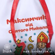 Мішечок подарунковий до Дня Миколая крупним планом, деталізація тексту персоналізації та фактури білого габардину.