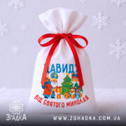 Мішечок подарунки Миколай на білому тлі зі сніжинками, загальний вигляд виробу 20×30 см.