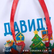 Мішечок подарунки Миколай — крупний план друку та червоної стрічки, видний текст “Давиду”.