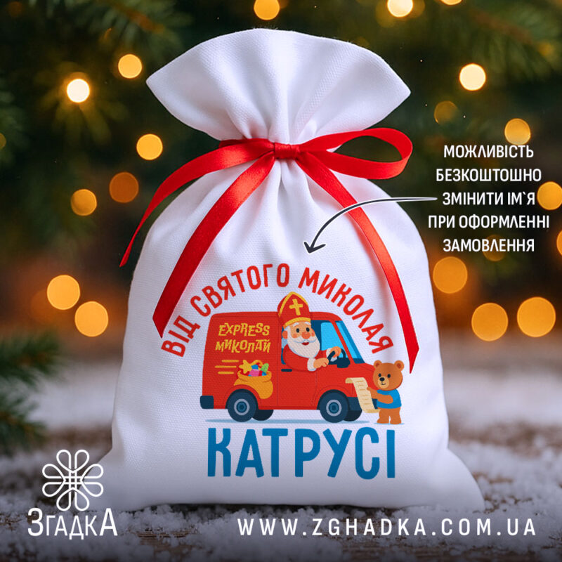 Мішечок від Миколая з іменем Катрусі, білий габардин, червона стрічка, фон — ялинкові вогники.
