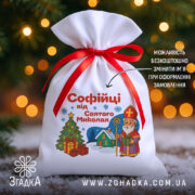 Подарунковий Іменний Мішечок до Миколая на фоні ялинки й вогників, білий габардин 20×30 см із червоною стрічкою, принт Миколай, ялинка і подарунки.