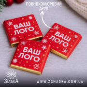 Шоколадки з логотипом у червоній святковій етикетці зі сніжинками.