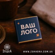 Шоколадки з логотипом у темно-синій преміальній етикетці на дерев’яному тлі.