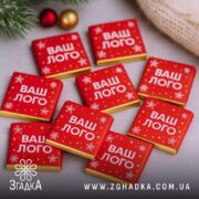 Шоколадки з логотипом у новорічному дизайні, кілька червоних плиток на фоні сніжинок.