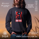 Світшот кіт do it, чорний колір, фронтальний ракурс, фон з м'яким освітленням, принт з малюнком кота, що курить, та написом 'DO IT!', кругла горловина, манжети на рукавах, трикотажна резинка на поясі, фактура м'яка та приємна на дотик.