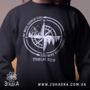 Світшот псалом компас, чорного кольору, з близьким ракурсом на верхню частину, фон нейтральний. Принт з компасом та текстом, білого кольору, кругла горловина, манжети, трикотажна резинка на поясі, фактура м'яка та приємна на дотик.