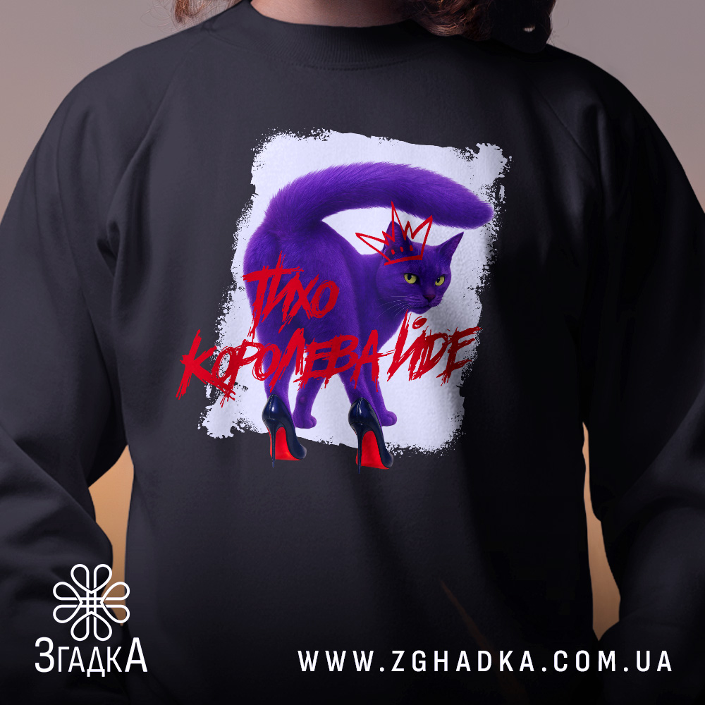 Світшот тихо королева йде, чорного кольору, з круглою горловиною, крупний план на принт з фіолетовим котом у червоних туфлях, фон розмитий, манжети та трикотажна резинка на поясі, фактура м'яка та комфортна.