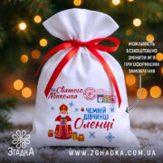 Торбинка Святого Миколая на снігу з червоною стрічкою та іменним принтом для дівчинки.