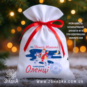 Торбинка від Святого Миколая на білому габардині з червоною стрічкою та принтом Святого Миколая біля ялинки.