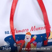 Крупний план тканини Торбинка від Святого Миколая з деталями принта і червоною стрічкою.