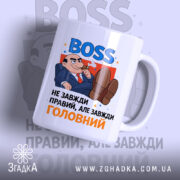 Чашка BOSS для офісу, біла, зображена з фронтального ракурсу, фон світло-сірий з розмитими елементами, принт містить напис 'BOSS' синього кольору та карикатуру чоловіка в костюмі, ручка стандартна, край рівний, глянцевий.