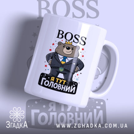 Чашка BOSS я головний, біла з кольоровим принтом, показує ведмедя в костюмі з короною, напис 'Я ТУТ ГОЛОВНИЙ' на чорному фоні, ручка гладка, край рівний, глянцева поверхня.