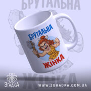Чашка брутальна жінка, біла, зображення зліва, фон світло-сірий, принт з малюнком жінки в кам'яному віці з молотом, напис 'Брутальна жінка' синім кольором, ручка стандартна, край рівний, матова поверхня.