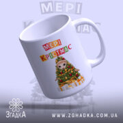 Чашка Магічний час Різдва, біла, з ракурсом зліва, фон світло-фіолетовий, принт з ведмедиком на ялинці та написом 'МЕРІ КРІСТМАС', ручка округла, край гладкий, глянцевий.