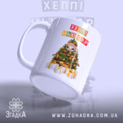 Чашка новорічна казка з подарунками, біла, з бокового ракурсу, на фоні світло-сірого кольору, принт з новорічною ялинкою та написом 'ХЕППІ НЬЮ ЄР', ручка округла, край гладкий, глянцева поверхня.