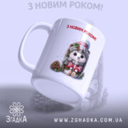 Чашка Подарунок на свята. Біла чашка з малюнком їжачка у святковому одязі, з боку видно ручку. Край чашки рівний, глянцевий. Напис 'З НОВИМ РОКОМ!' червоного кольору на передній частині.