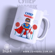 Чашка супер чоловік, біла, з малюнком супергероя, що носить червоний плащ і синій костюм, на фоні блакитного неба з хмарами та кольоровими цукерками, ручка кругла, край рівний, глянцева поверхня.