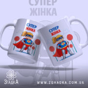 Чашка супер жінка, дві білих чашки з однаковим принтом, одна з них злегка нахилена, на фоні кольорових цукерок, ручки класичні, край рівний, глянцева поверхня.