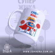 Чашка супер жінка, біла з яскравим принтом, показує супергероїню з жовтими волоссям у масці та червоному плащі, з боку, на фоні кольорових цукерок, ручка класична, край рівний, глянцева поверхня.