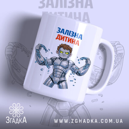 Чашка залізна дитина, біла з кольоровим принтом, показує персонажа з коротким волоссям у сірому костюмі, що тримає ланцюги. Ручка чашки гладка, край рівний, поверхня має глянець, фон світло-сірий з розмитим зображенням.