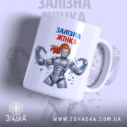 Чашка залізна жінка, біла з кольоровим принтом, зображення зліва, фон світло-сірий, принт з малюнком залізної жінки з червоним волоссям, ручка класична, край рівний, глянцева поверхня.